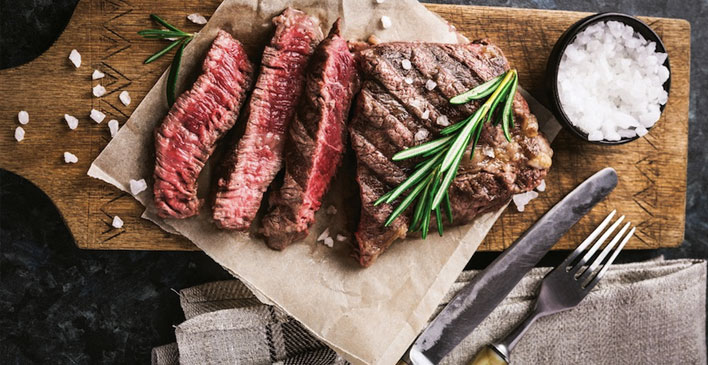 Carne Maturatta Friboi para churrasco com sal grosso ao lado de uma faca e garfo de churrasco