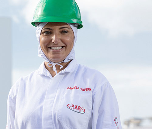 Mulher usando capacete verde e uniforme da JBS